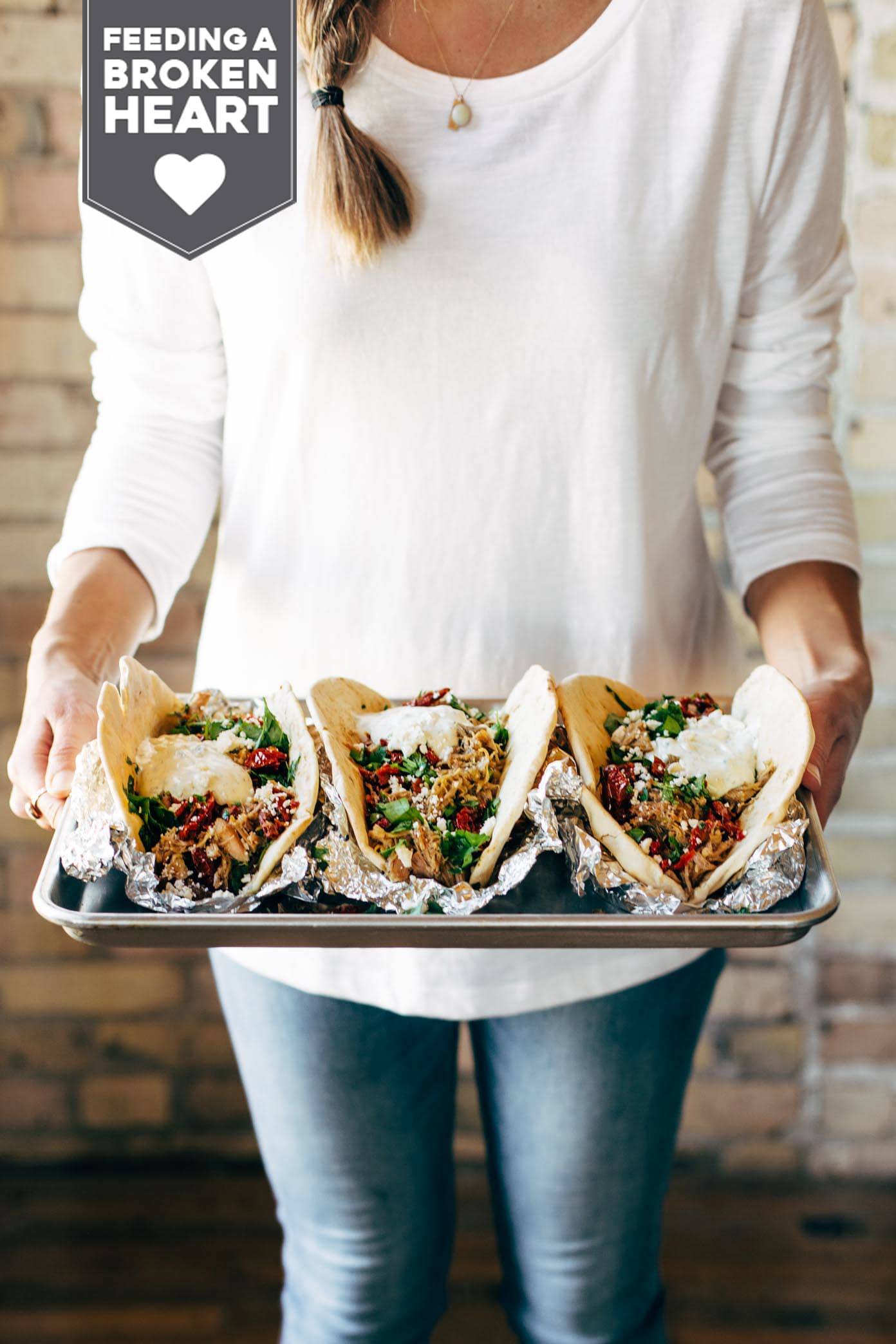 Woman holding a tray of Everything Greek Pork Pitas.