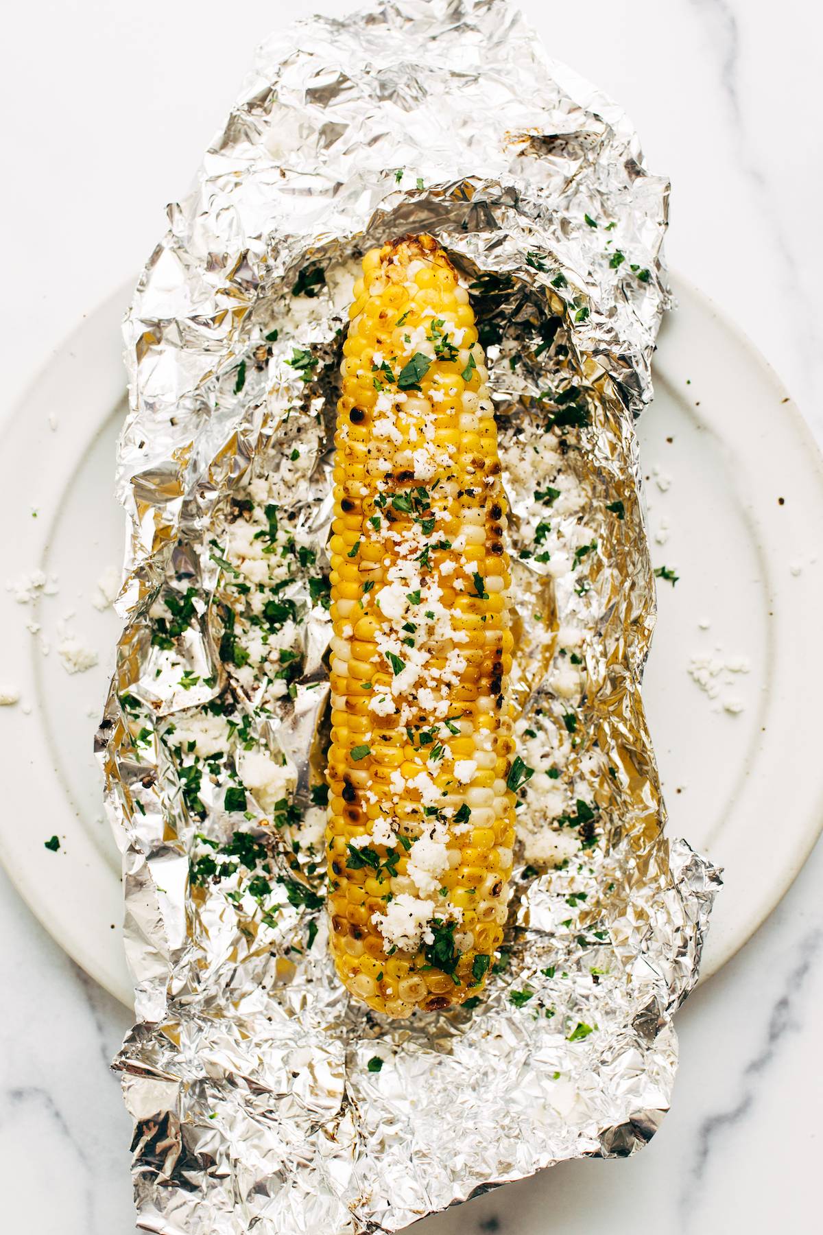 Grilled ear of corn on top of aluminum foil.