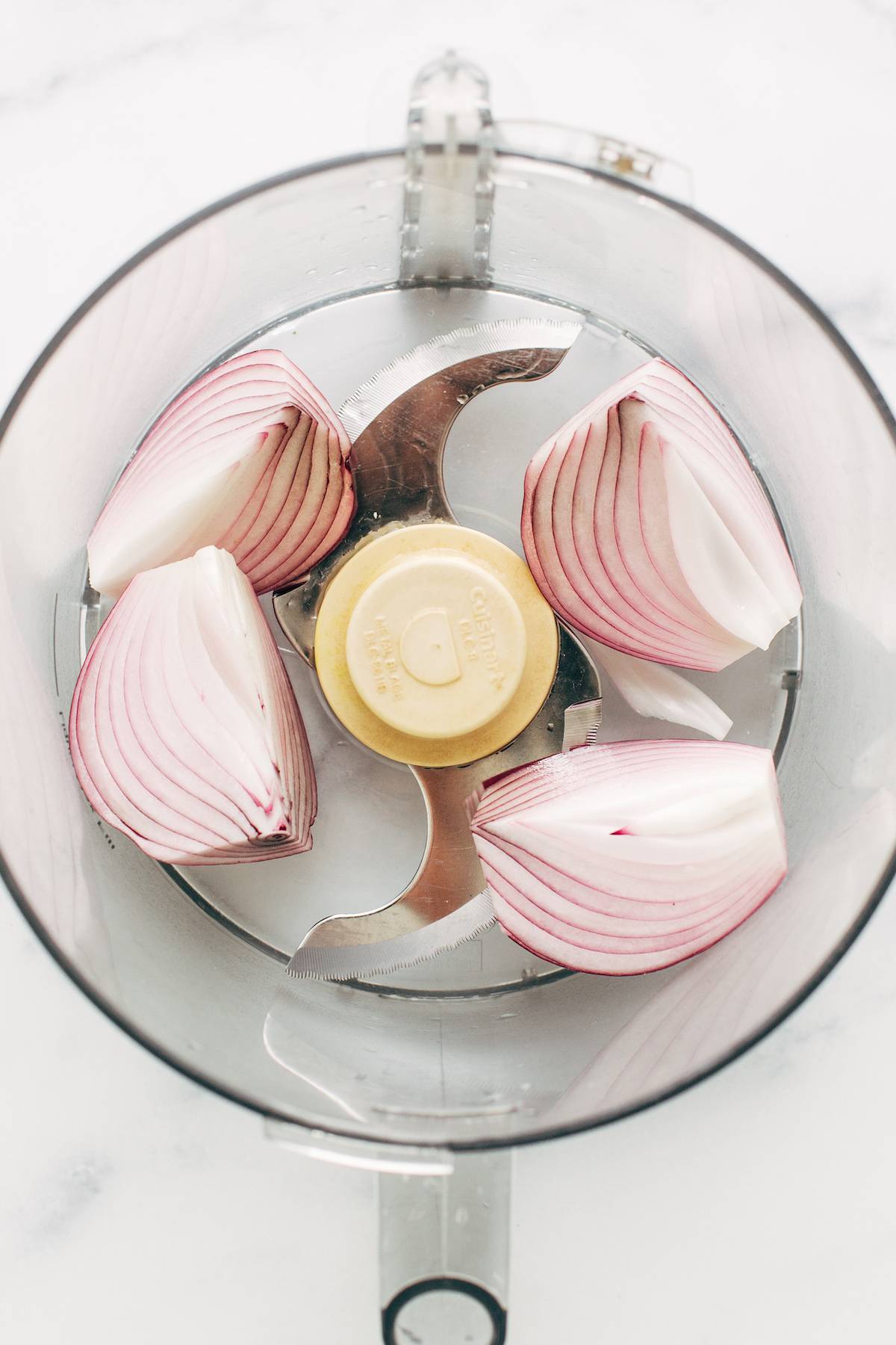 Four sections of an onion in a food processor.