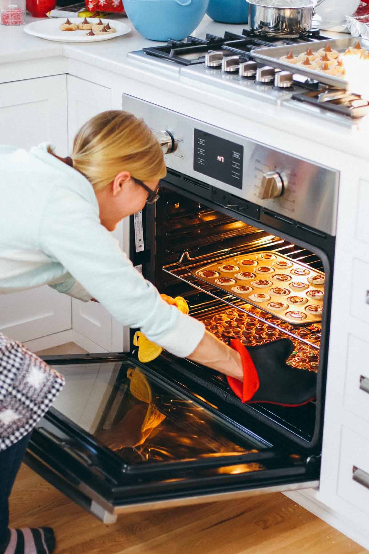 Woman pulling cookies out of an oven.