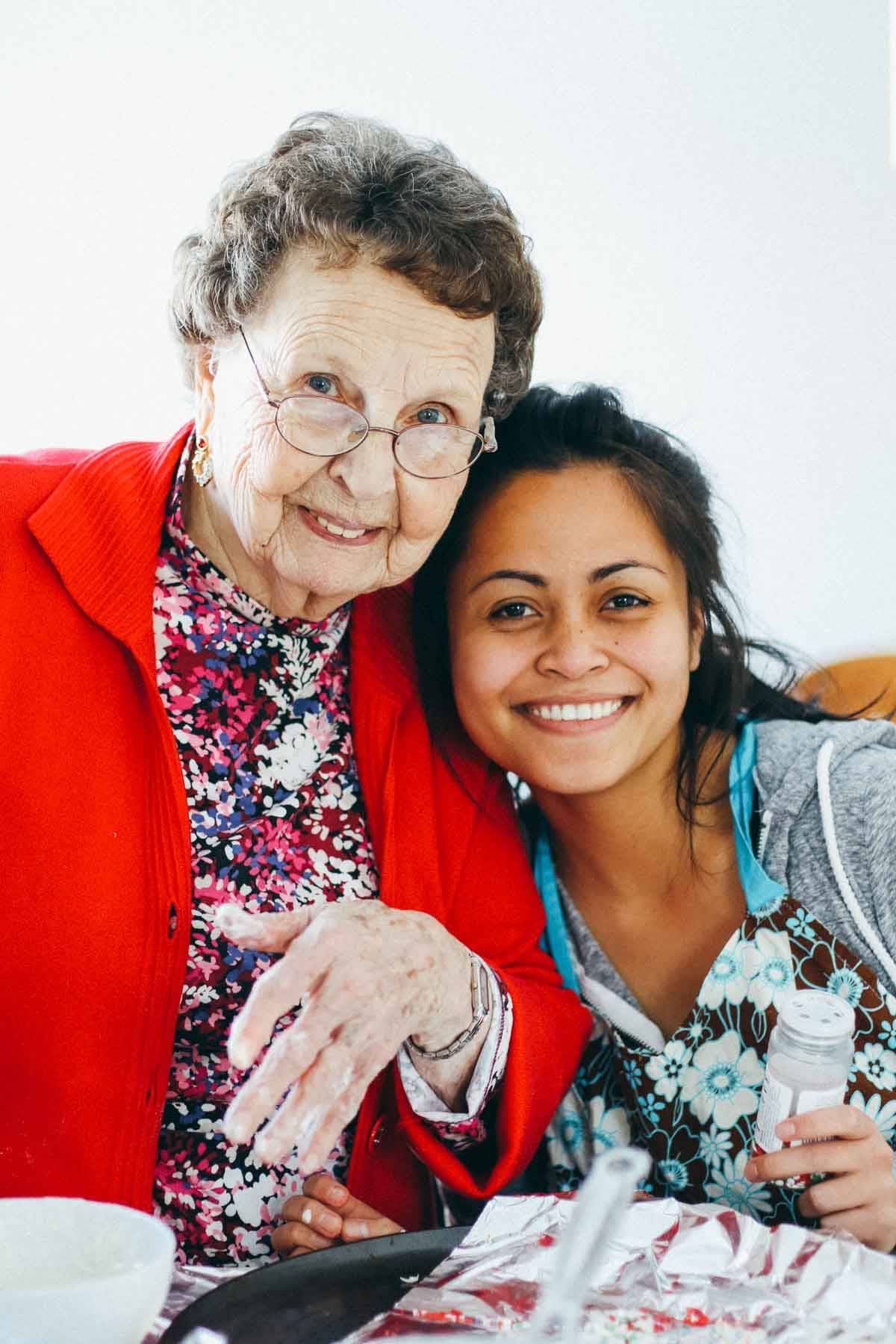 Elderly woman smiling with a young girl.