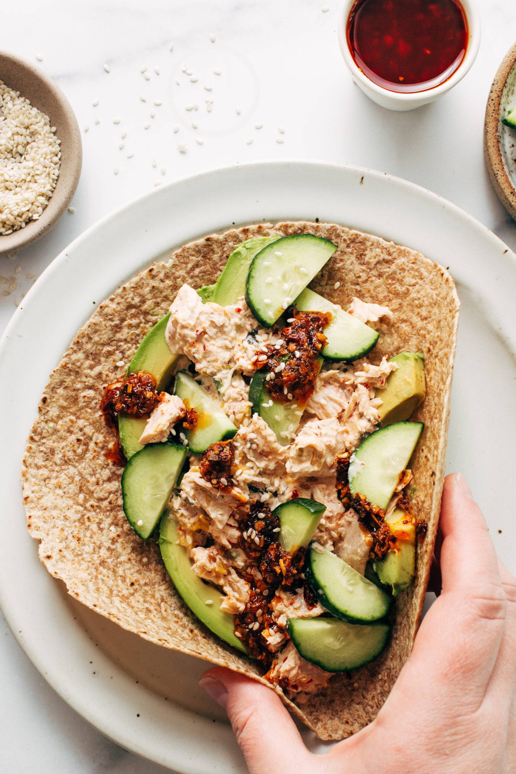 White hand grabbing a kimchi tuna salad wrap