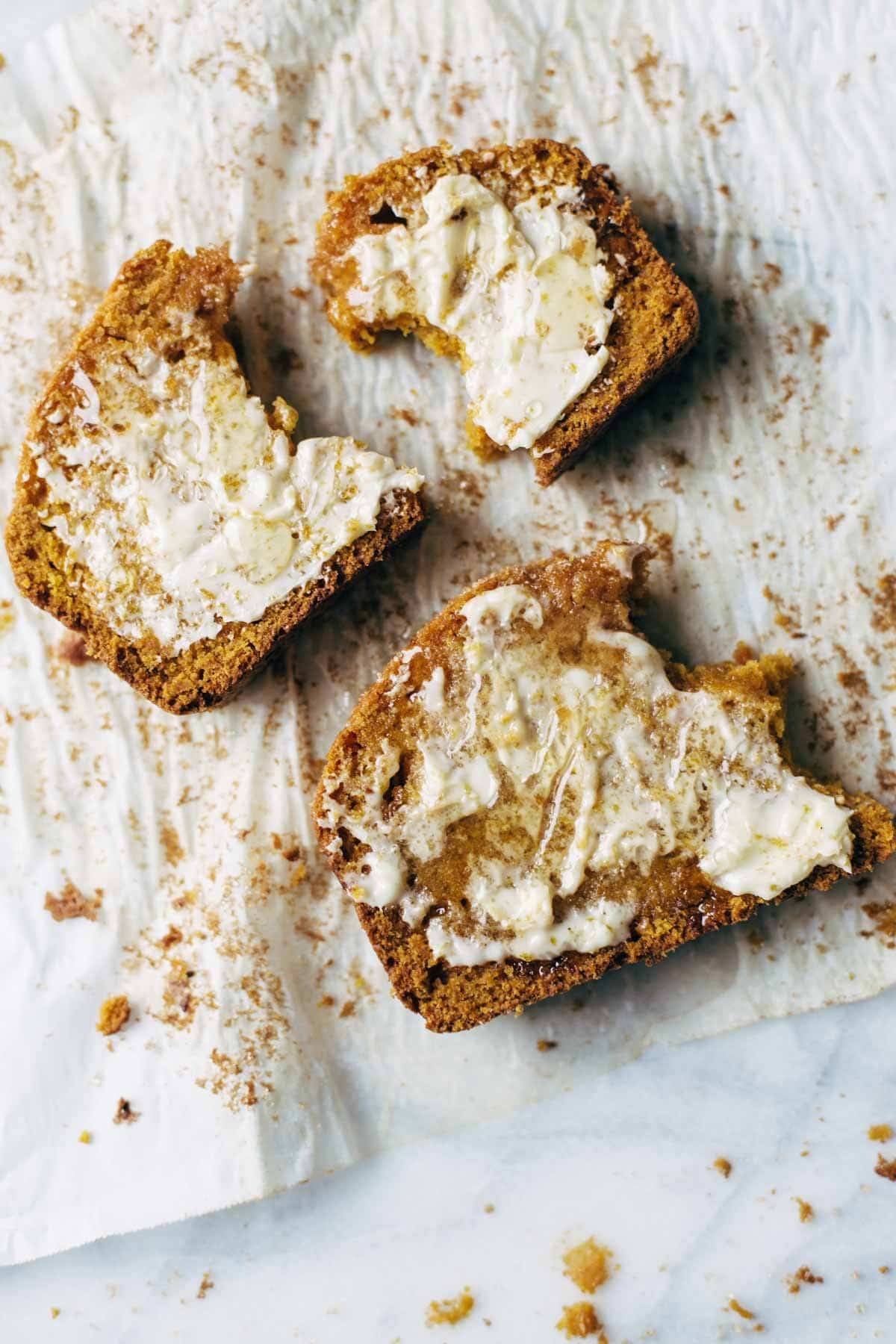 Pumpkin bread on parchment with butter and honey.