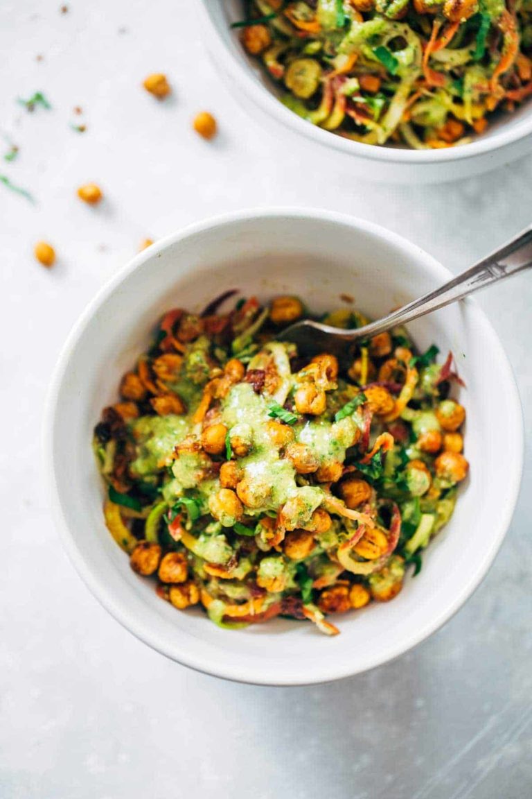 Spiralized veggies in a bowl with chickpeas and green sauce.