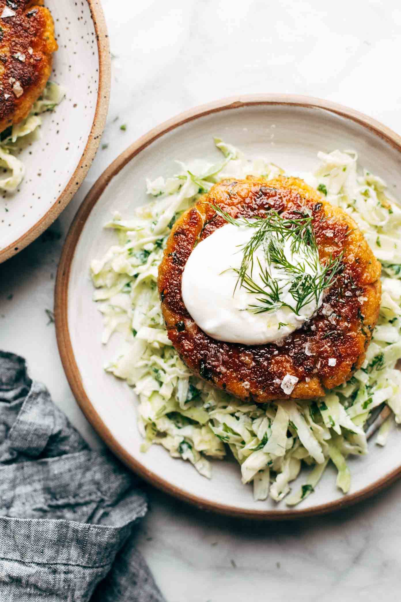 Salmon burgers with slaw on two plates.