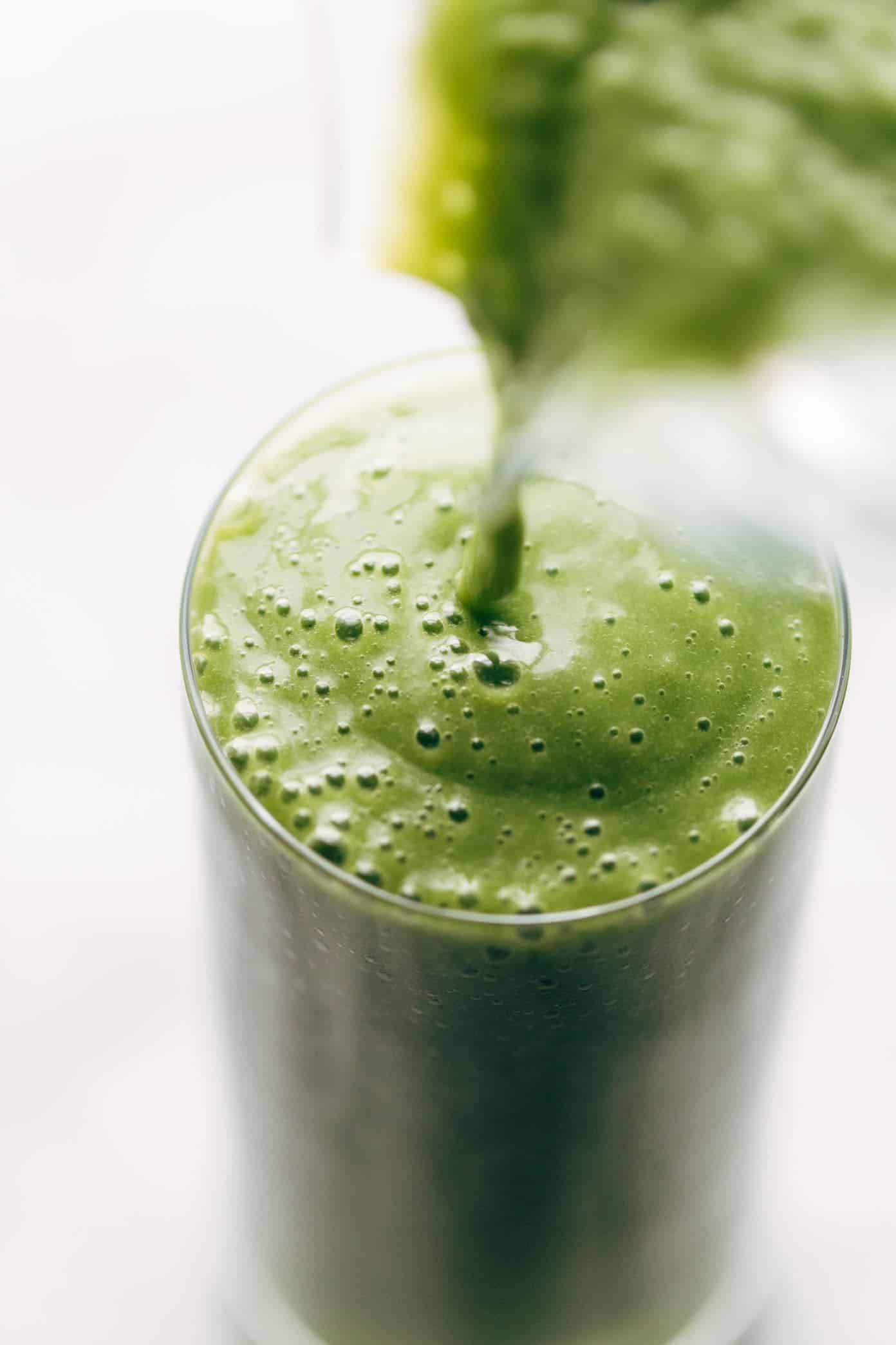 Green smoothie poured into glass.