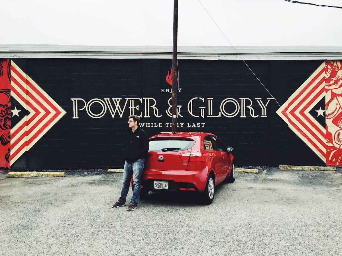 Man standing next to a red vehicle.